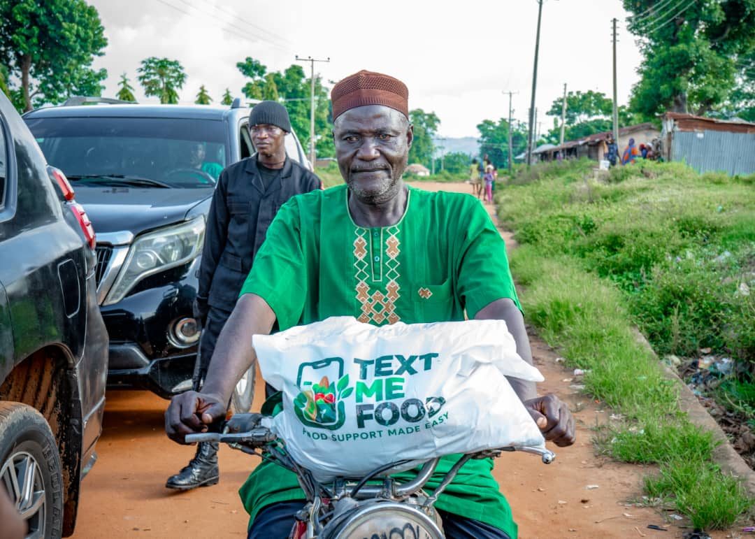 TMF beneficiary carrying a Text Me Food bag home on his motorcycle